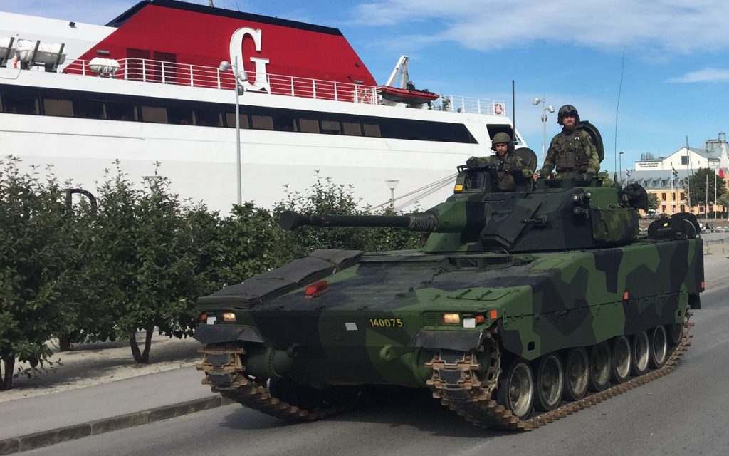 Pansarvagn med svenska soldater passerar en Gotlandsfärja i Visby.foto: Joakim Elovsson/Försvarsmakten